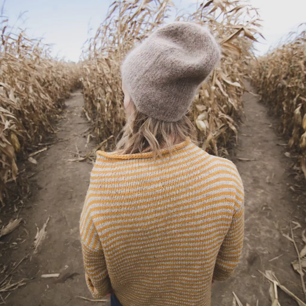 A lady in a field, having to choose one from two paths.