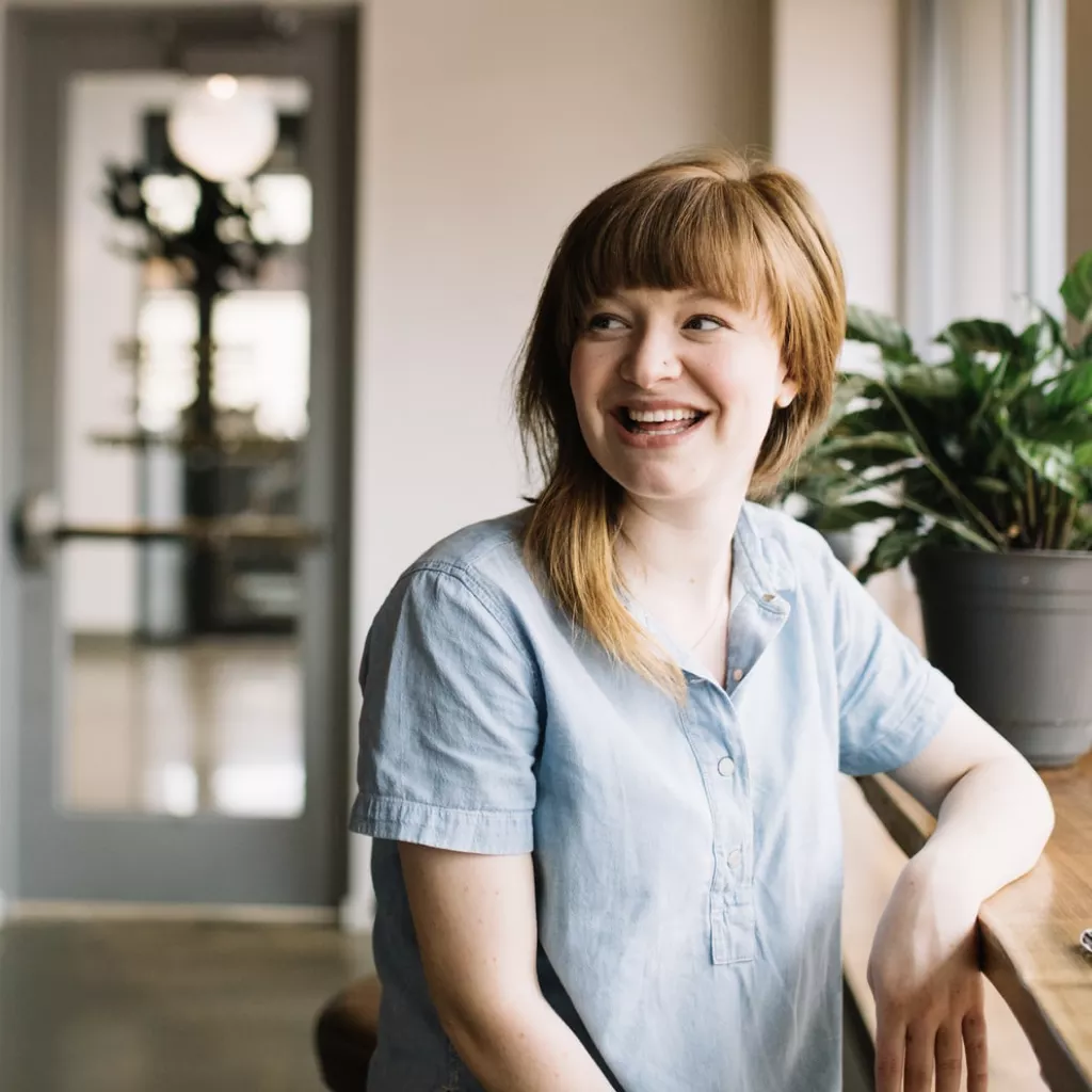 A lady at work, turning back to someone and smiling at them.