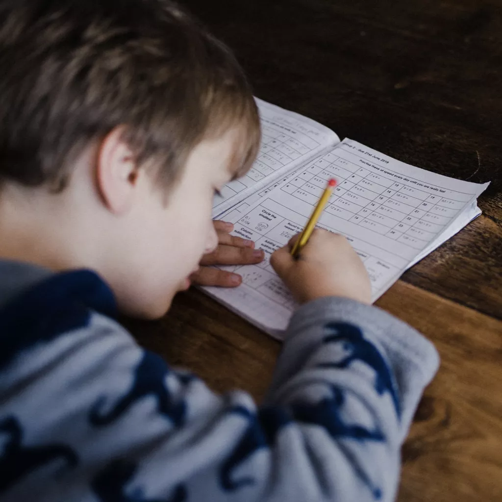 A boy writing in his school book.