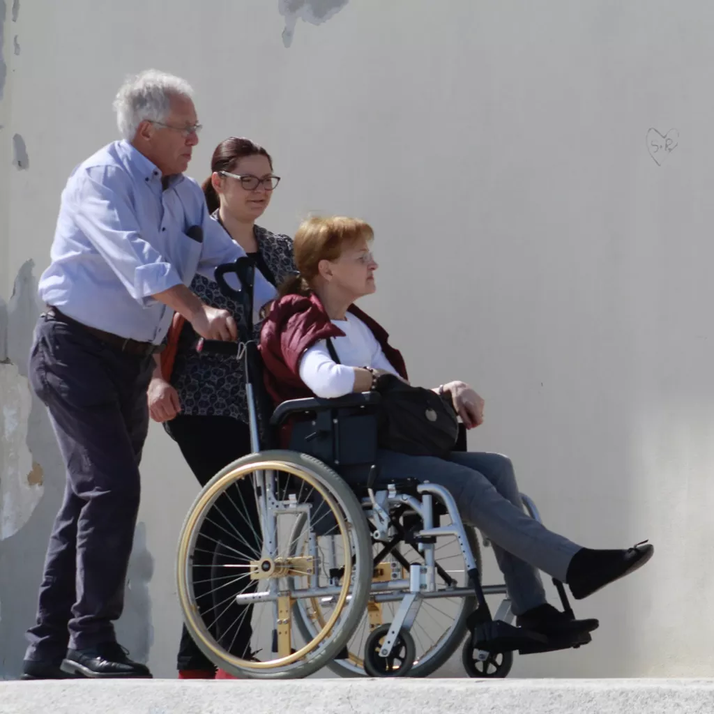 A lady being pushed in a wheel chair.