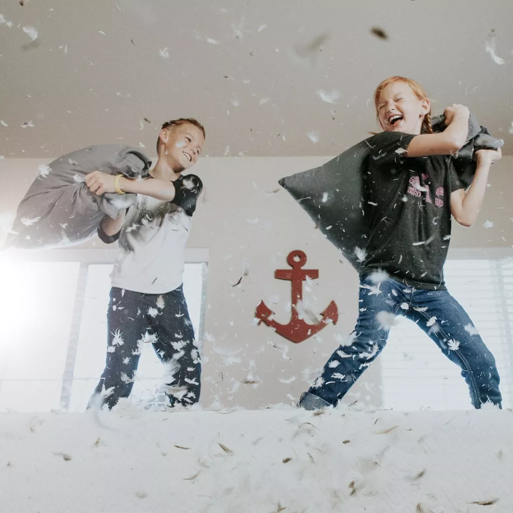 Two boys in a pillow fight.