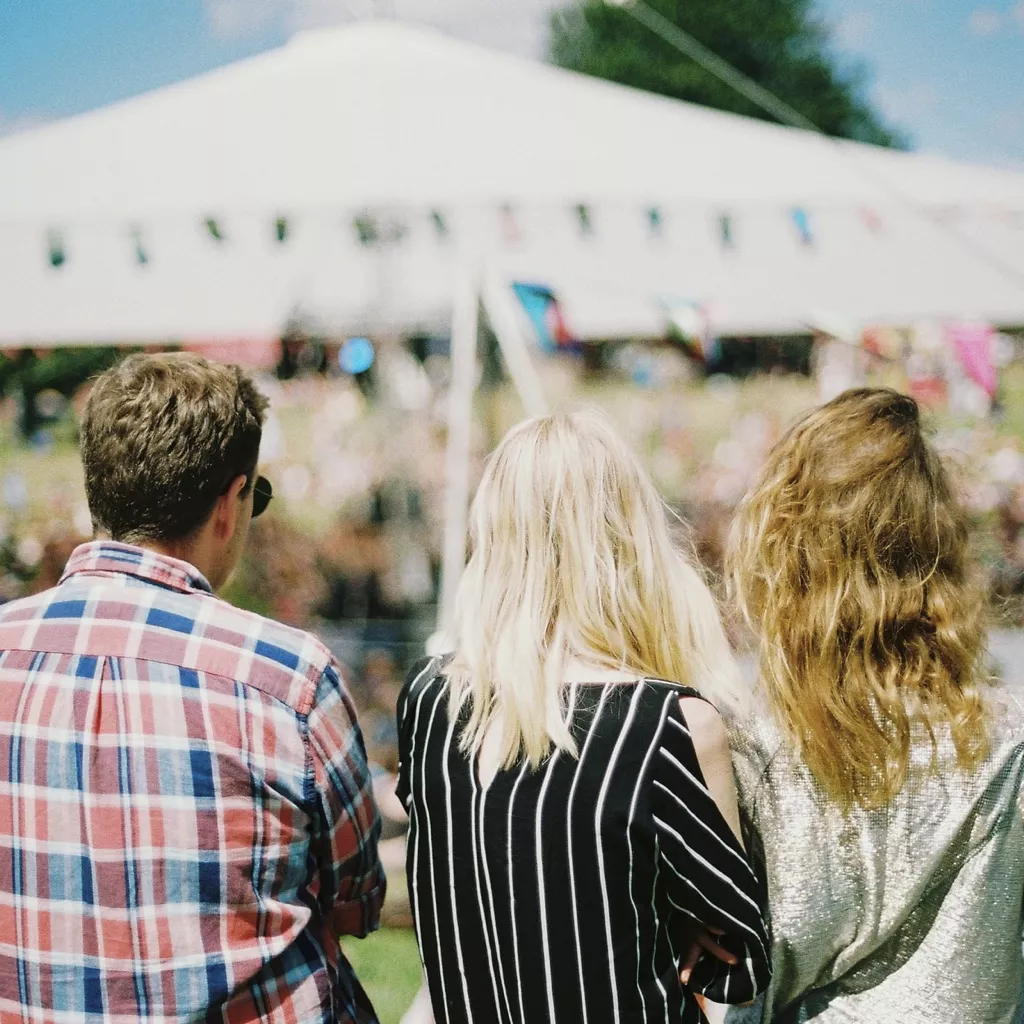 Three people in front of a marquee.