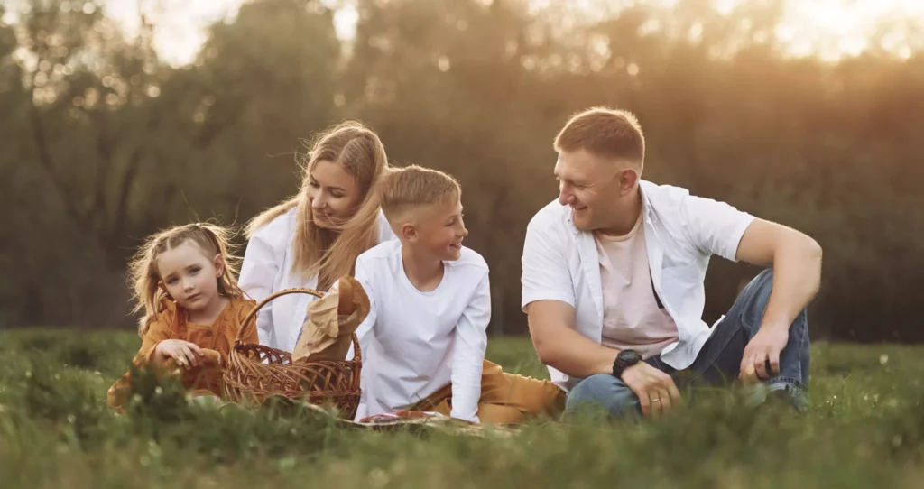 A happy family sat outside having a picnic. 