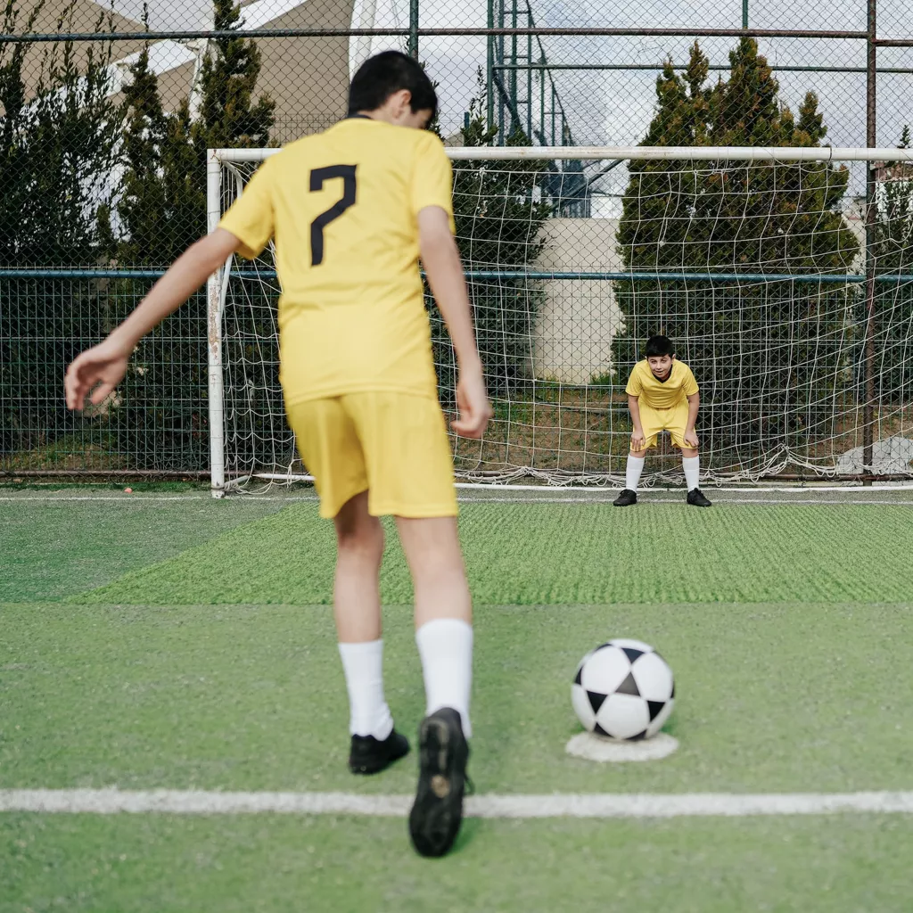 A boy taking a football penalty.