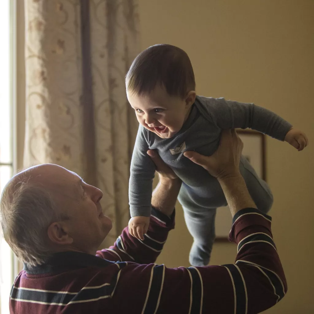 A grandfather lifting his grandchild.