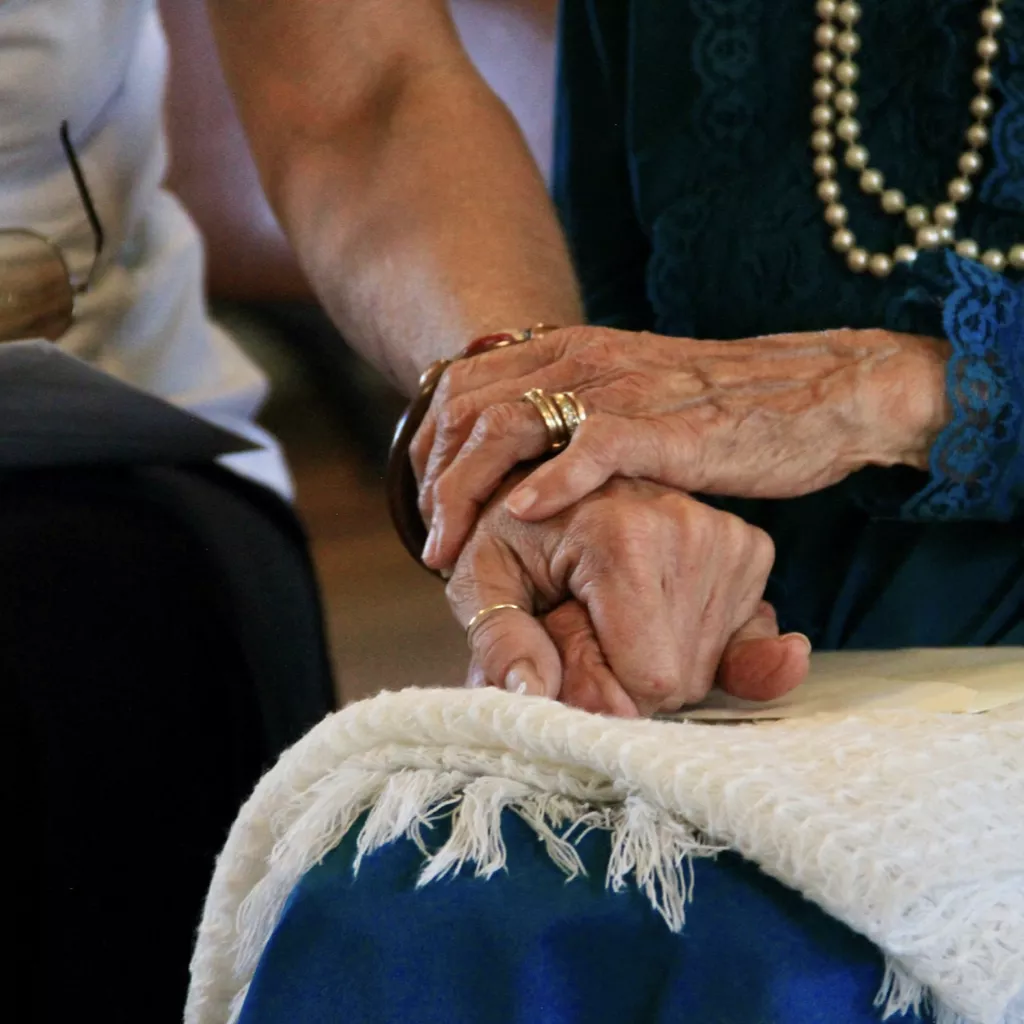 An elderly mother holds her daughter's arm.