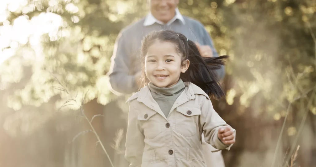 A happy girl followed by her Grandfather.