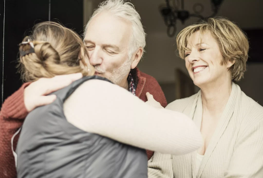 Parents kissing their adult daughter goodbye.