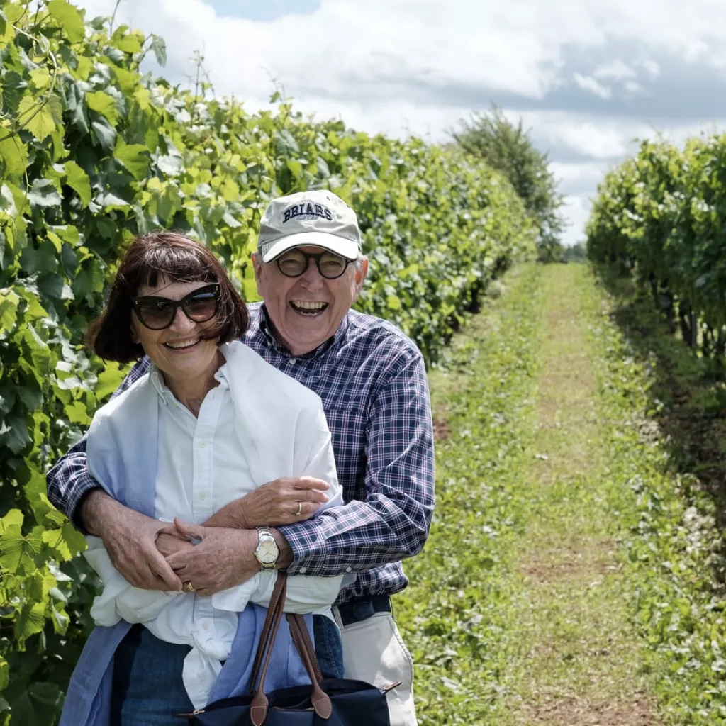 A retired couple smiling and having a hug.