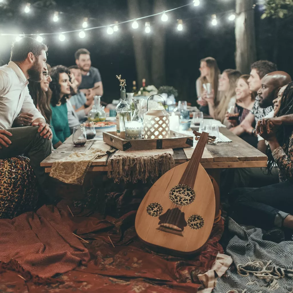 A lot of friends gather around a table outside.