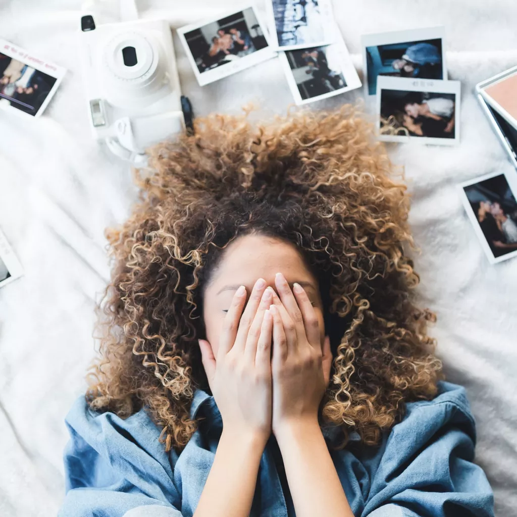 A woman lying down surrounded by printed photos.