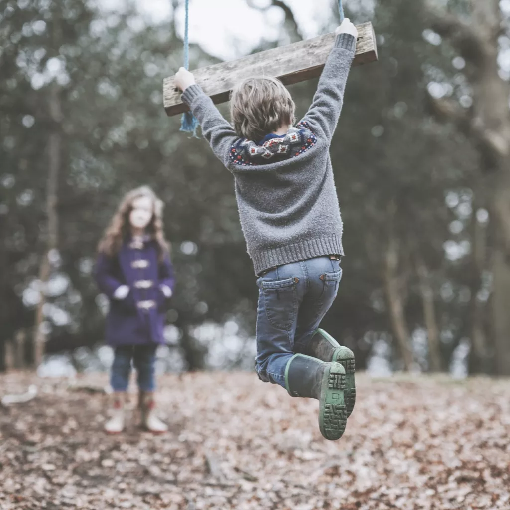 A boy hanging on a swing.