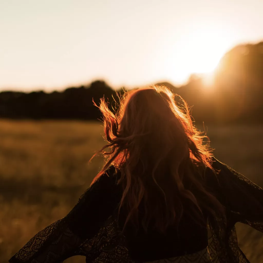 A lady running in a field as the sun sets.